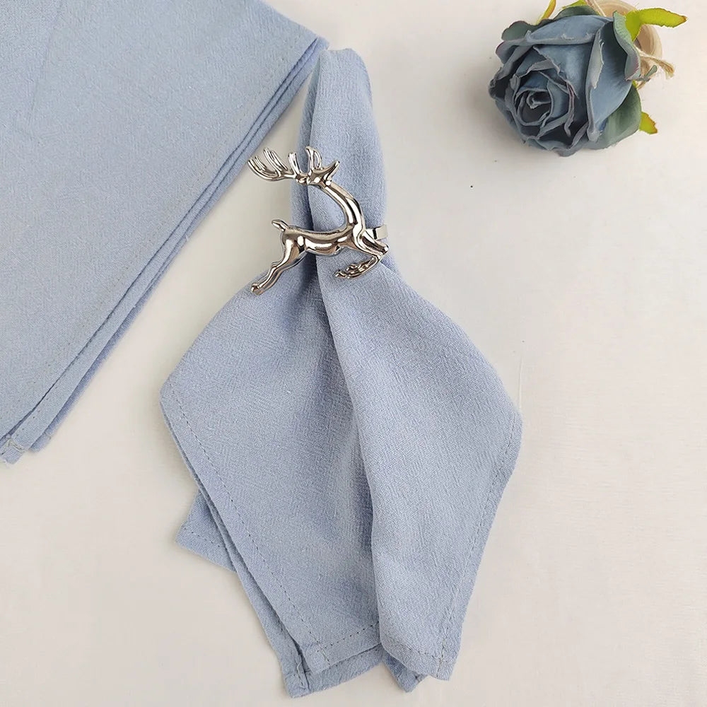 Une nappe grise élégante avec une décoration de broche en métal argenté en forme de cervidé, créant une scène apaisante.