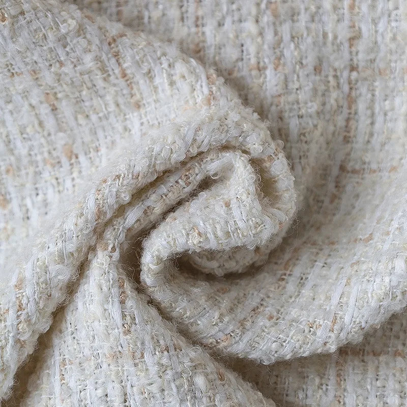 Gros plan sur une texture en coton blanc et beige, montrant un motif de fibres enchevêtrées.