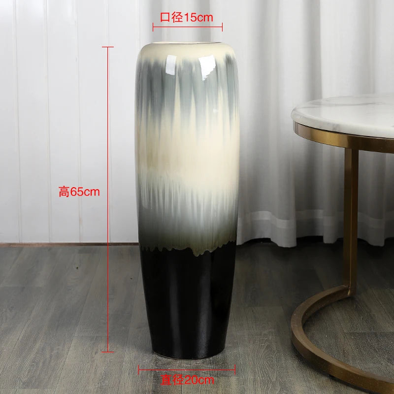 Vase décoratif élégant avec un design dégradé de couleurs neutres, mesurant 65 cm de hauteur pour un diamètre de 15 cm, posé sur un sol en bois foncé.