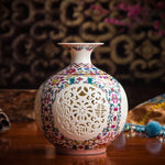 Vase décoratif en porcelaine blanche avec un motif floral multicolore ajouré et un design raffiné et élégant.