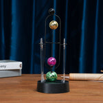 pendule newton sphères colorées structure métallique support transparent base circulaire décoration cinétique moderne