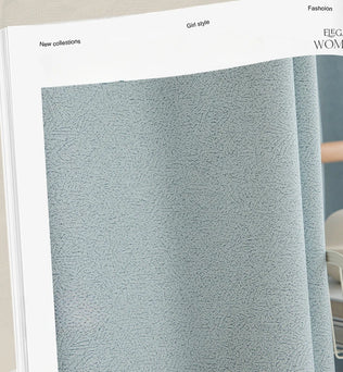 Zoom sur le tissu du rideau gris tendance mis en avant dans un catalogue, illustrant la finesse de sa texture et son tombé naturel.