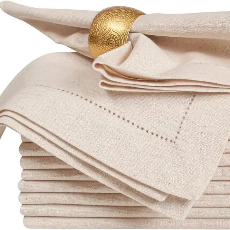 Serviettes de table beige et bracelet doré avec motifs décoratifs.