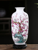 Un magnifique vase en porcelaine blanche décoré de fleurs de cerisier roses épanouies et d'un motif de paon sur un fond sombre, créant une scène élégante et raffinée.