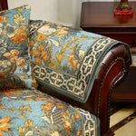 Un fauteuil en bois sculpté avec un riche motif floral dans des tons de bleu, de jaune et d'orange, conçu dans un style décoratif vintage.