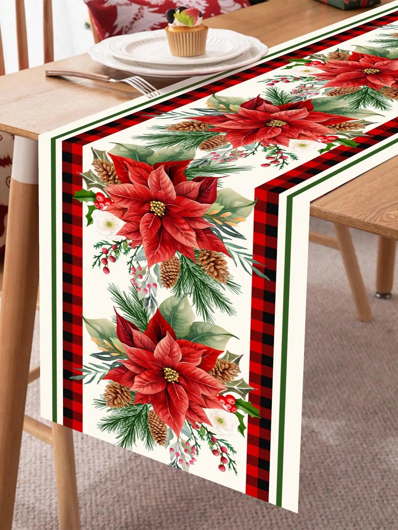 Chemin de table de Noël avec motifs de poinsettias rouges, de branches de pins et de cônes, créant une ambiance festive et chaleureuse pour la période des fêtes.