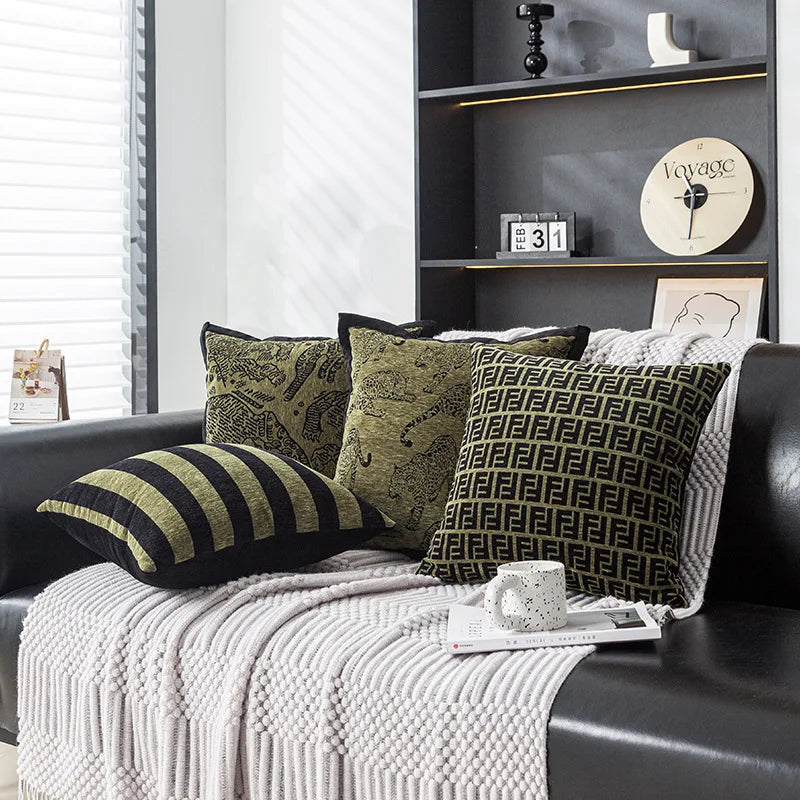 Coussins décoratifs en motif rayures et géométrique sur un canapé gris, entouré d'étagères avec des accessoires de décoration.