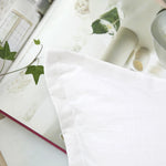 Gros plan d'une couverture blanche, de feuilles vertes et d'autres objets décorés, créant une ambiance apaisante et naturelle.