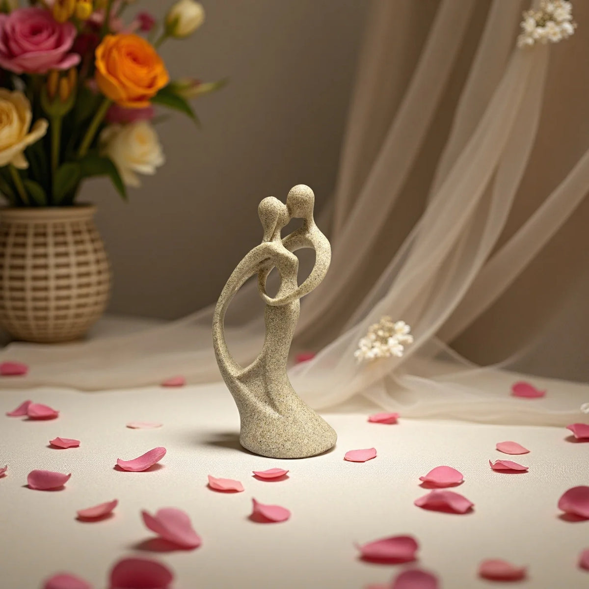 statuette résine couple enlacé beige texture sable romantique fleurs blanches table verte