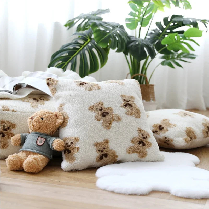 Un coussin doux et pelucheux orné de motifs de pattes, accompagné d'un petit ourson en peluche, dans un cadre de plantes vertes et luxuriantes.