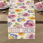 Chemin de table avec des fleurs colorées et l'inscription "Hello spring" indiquant l'arrivée du printemps.