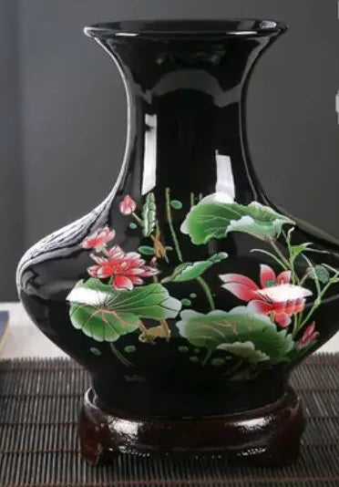 Vase en céramique noir orné de délicates fleurs roses épanouies sur un fond vert.