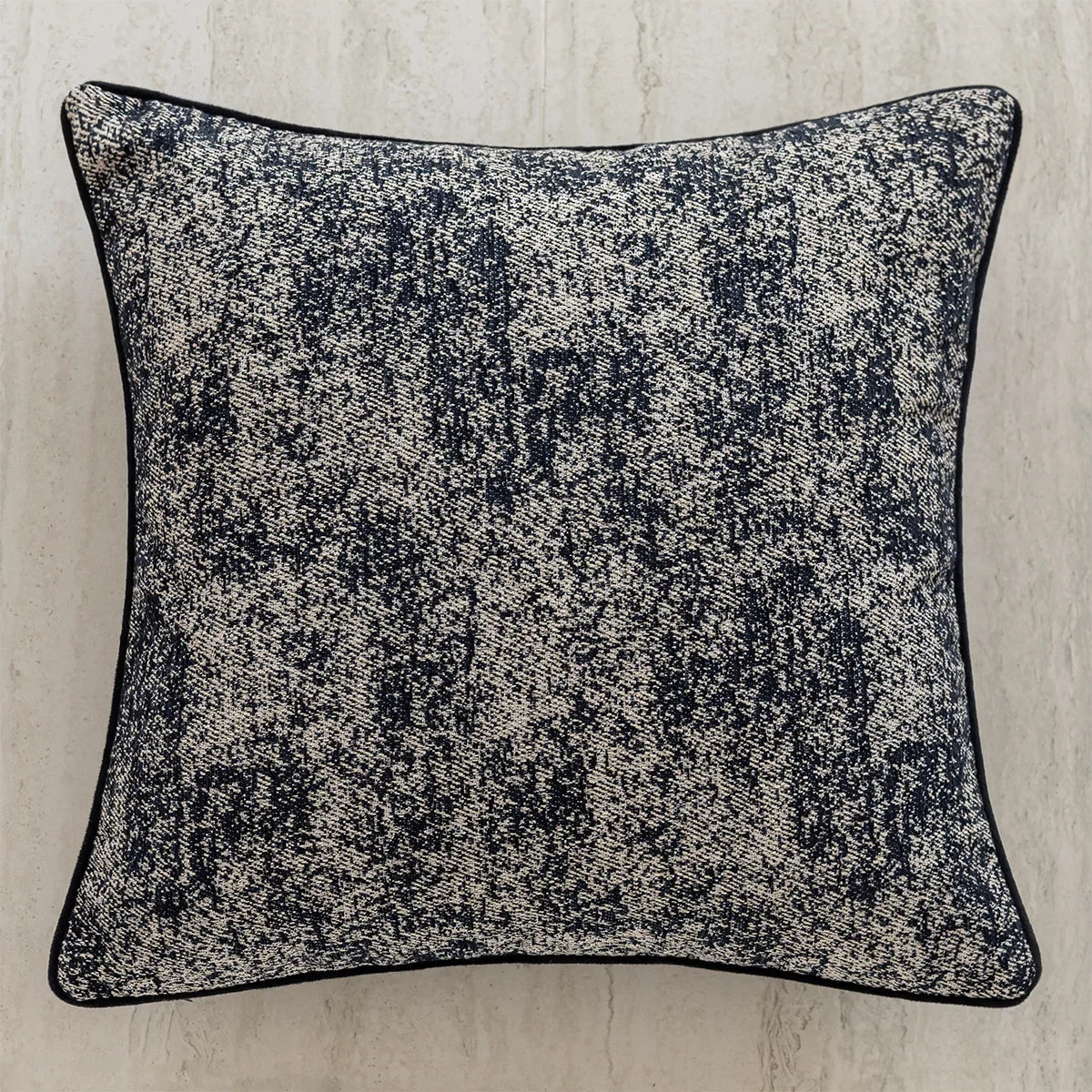 Coussin ornemental en tissu texturé noir et blanc, avec un motif abstrait qui ajoute de l'intérêt visuel.