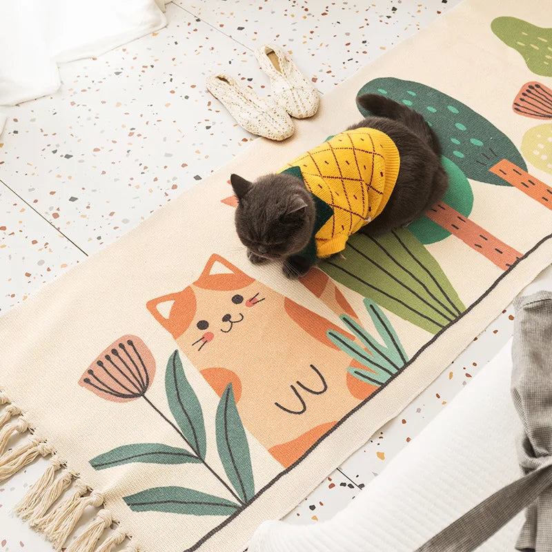 Un chat noir mignon vêtu d'un costume d'ananas joue sur un tapis décoratif coloré avec des motifs de plantes et d'animaux.