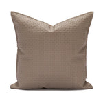 Coussin décoratif avec motif géométrique sur fond beige.