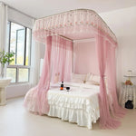 Chambre de style romantique avec un grand lit à baldaquin rose pastel et un linge de lit blanc.