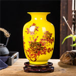 Un vase en céramique jaune vif décoré de fleurs de pivoines rouges.