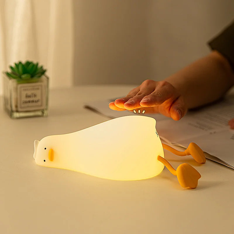 Veilleuse canard LED rechargeable en silicone bleue sur table de chevet