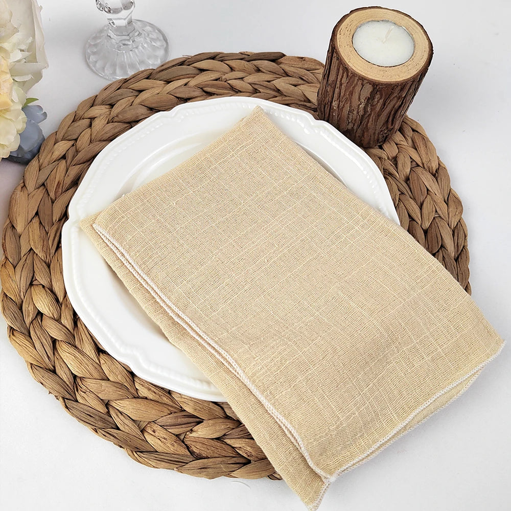 Serviette beige posée sur une assiette blanche sur un dessous de plat en tresse de jonc.