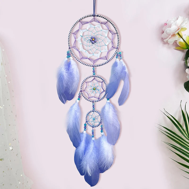 Un capteur de rêves décoratif et coloré, composé de plumes bleues et de cercles en corde, suspendu sur un fond clair avec des fleurs.