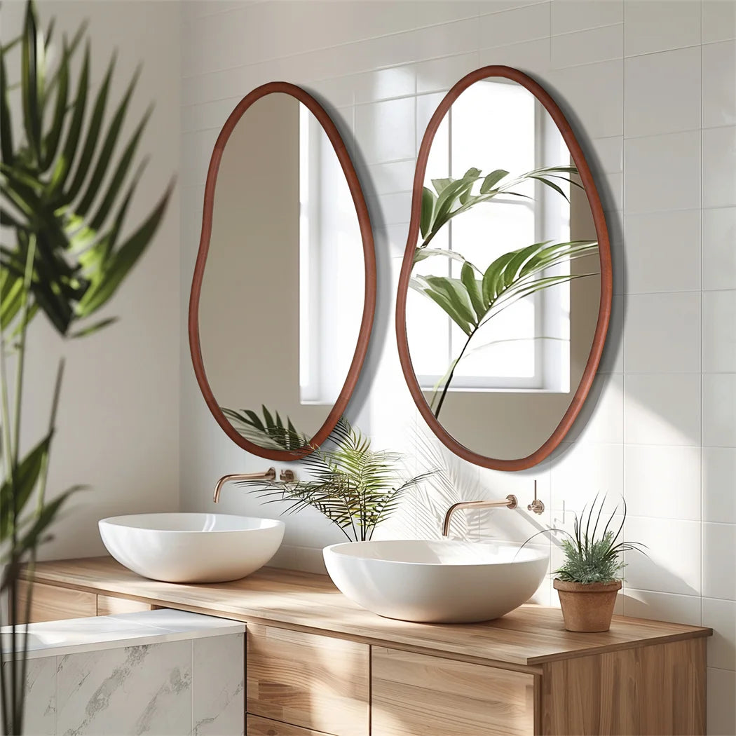 Le design minimaliste et élégant de cette salle de bain avec ses miroirs ovales en bois, ses lavabos blancs et son meuble en bois apporte une touche de nature grâce aux plantes vertes.