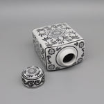 Boîte décorative en céramique avec motifs floraux monochromes.