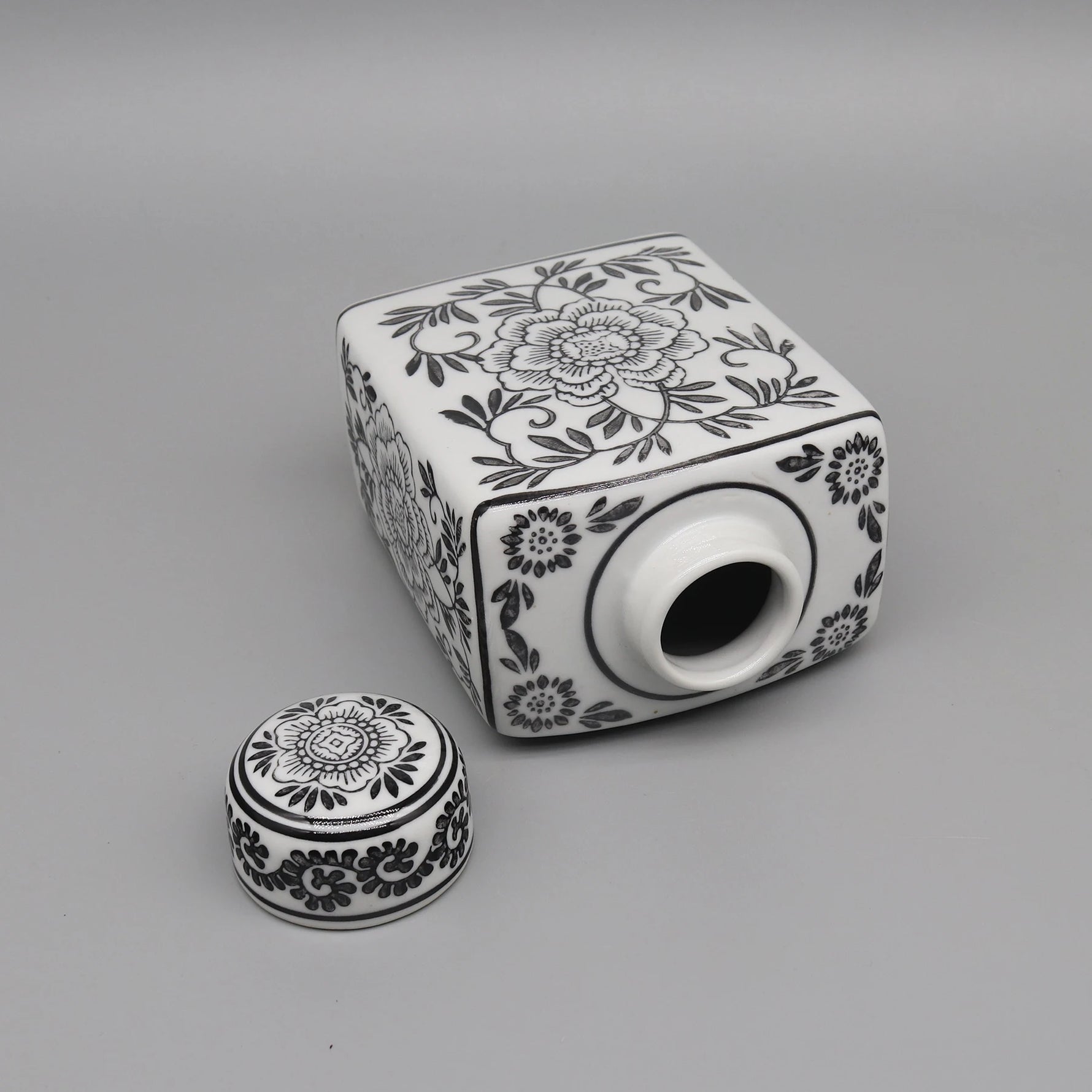 Boîte décorative en céramique avec motifs floraux monochromes.