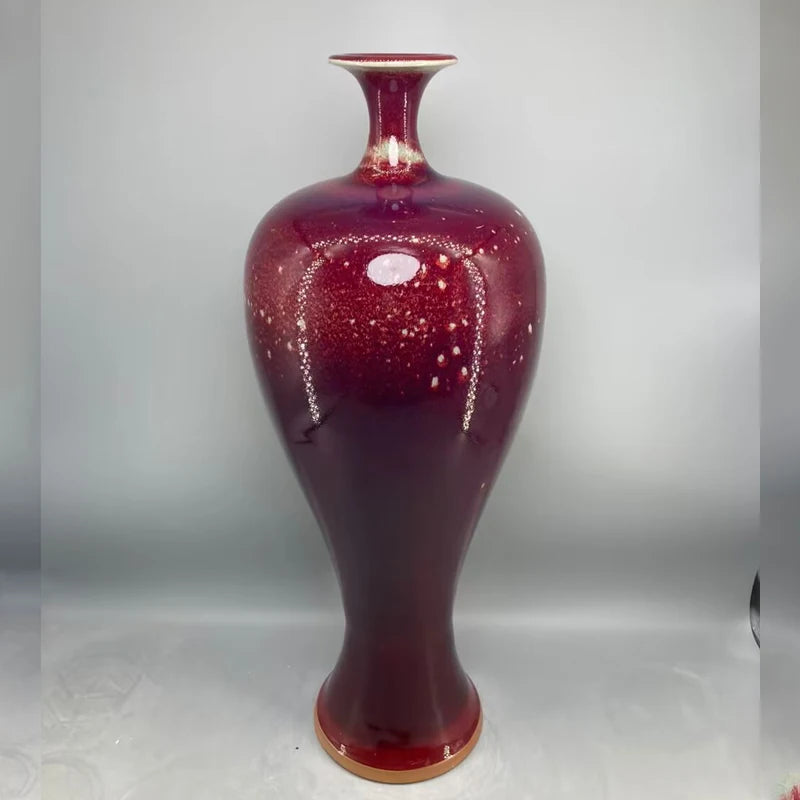 Un vase en céramique de couleur rouge profond, orné de motifs scintillants.