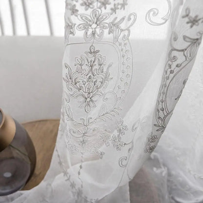 Détail raffiné des broderies délicates du voilage blanc, capturé sous la lumière du jour.