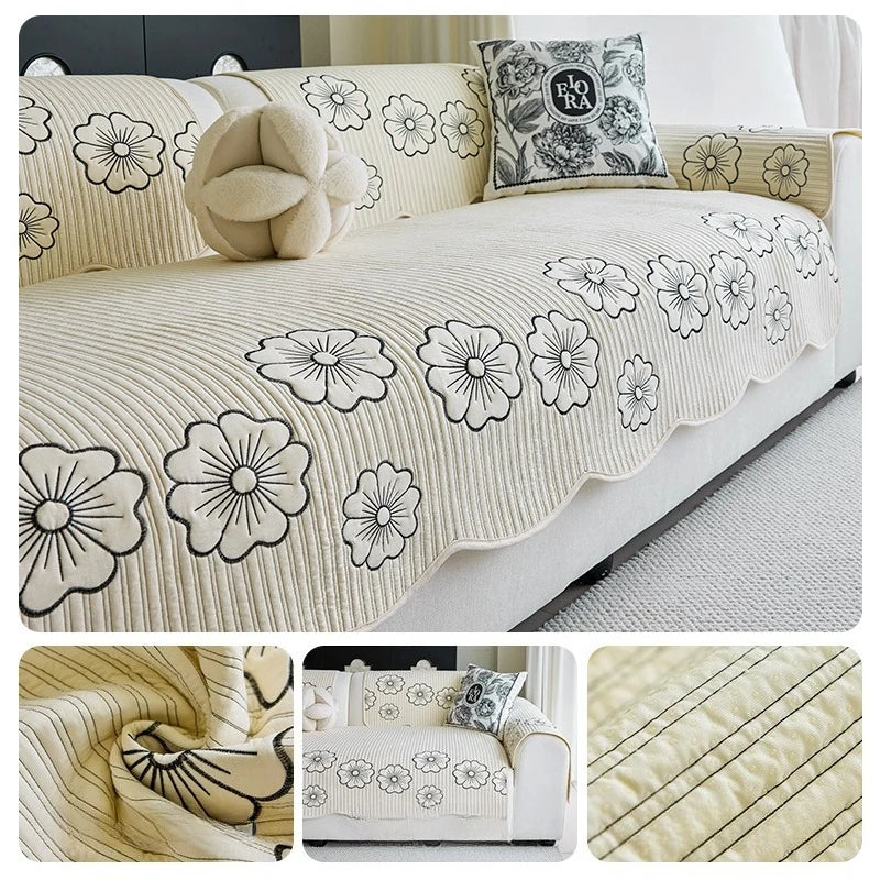Une housse de canapé douce et décorative avec des motifs de fleurs blanches et noires sur un fond beige rayé, complétée par un coussin orné et un élément en peluche, pour un bel ensemble de chambre ou de salon.