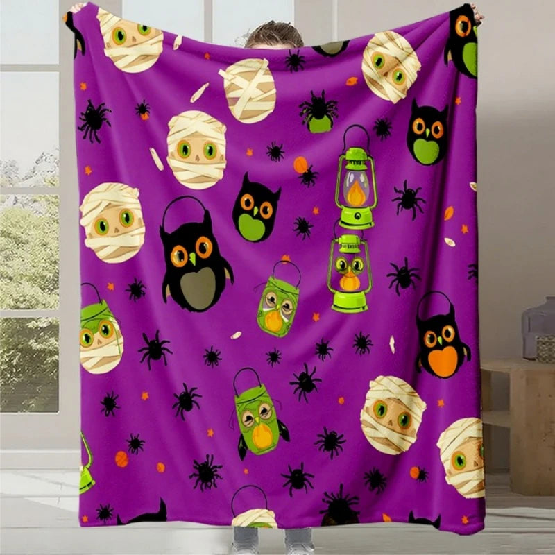Une couverture violette décorée de motifs d'animaux effrayants et de lanternes d'Halloween.