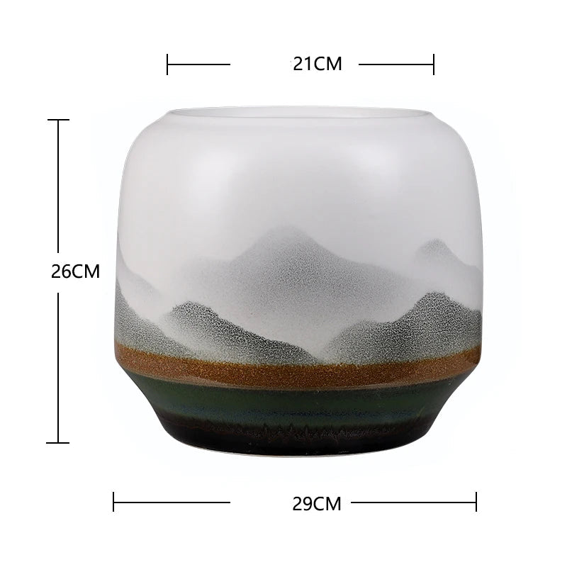 Vase en verre transparent avec motif de paysage montagneux en nuances de gris et de vert.