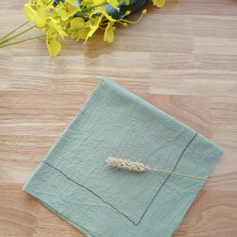 Serviette de table grise posée sur un bureau en bois avec un bouquet de fleurs jaunes à côté.