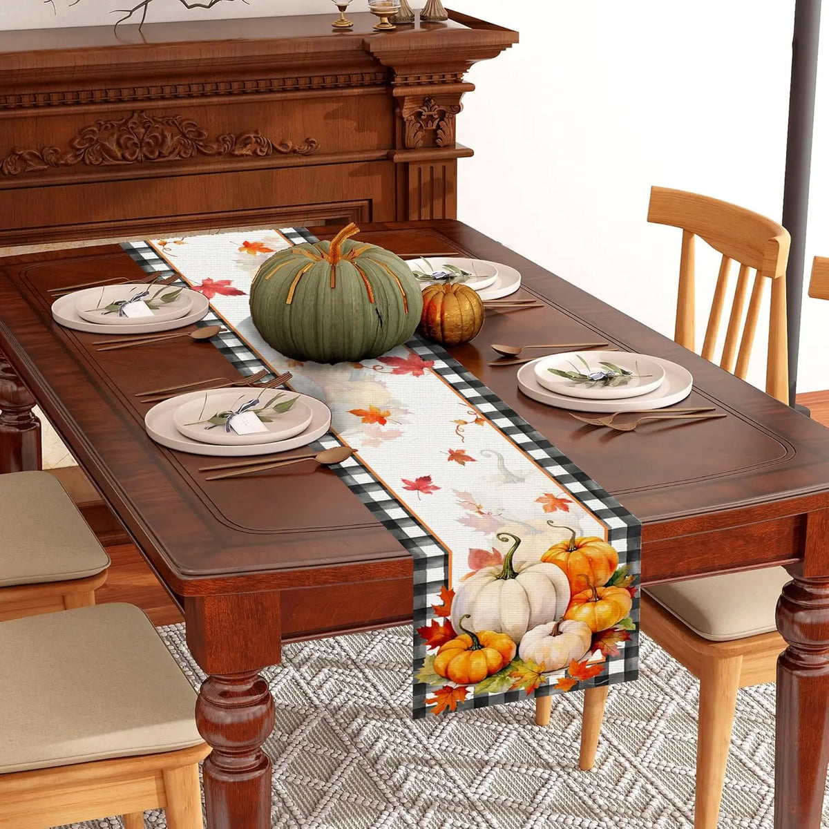 Une table de salle à manger en bois richement ornée avec des décorations d'automne, comprenant des citrouilles, des feuilles et une nappe à motifs.