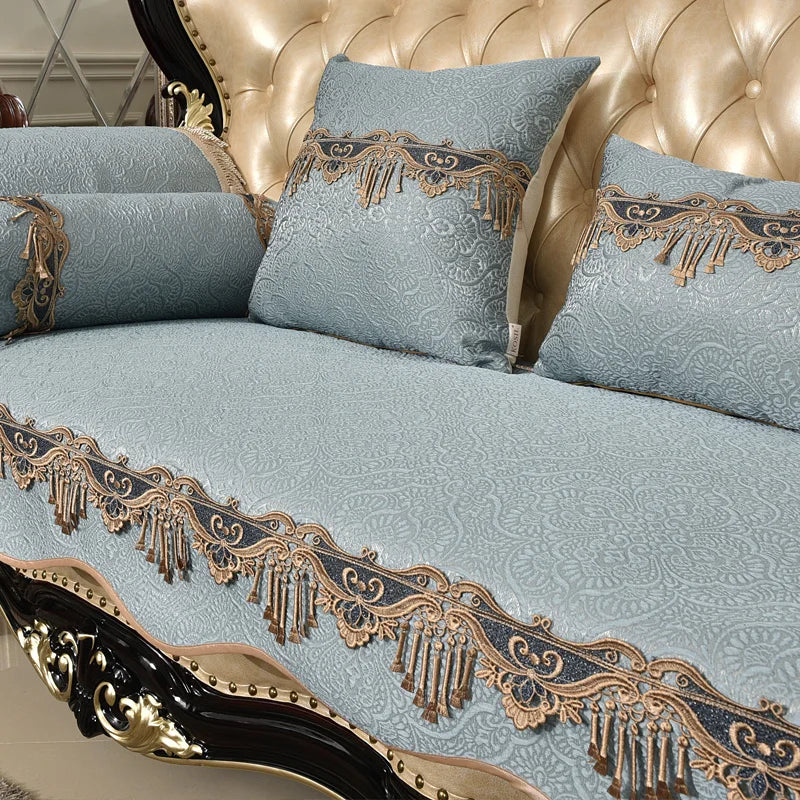 Un canapé vintage, aux motifs floraux bleus pastel, orné de décorations en métal doré, créant une atmosphère chic et élégante dans la pièce.