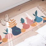 Motif abstrait coloré avec formes géométriques et feuilles stylisées sur un tapis posé sur un sol en bois.