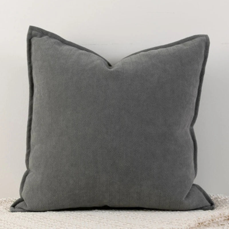 Coussin décoratif carré gris foncé avec des bords bien dessinés, créant une atmosphère chaleureuse et élégante dans un intérieur.