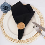 Élégante assiette blanche avec serviette de table noire, napperon tressé beige et décoration florale.
