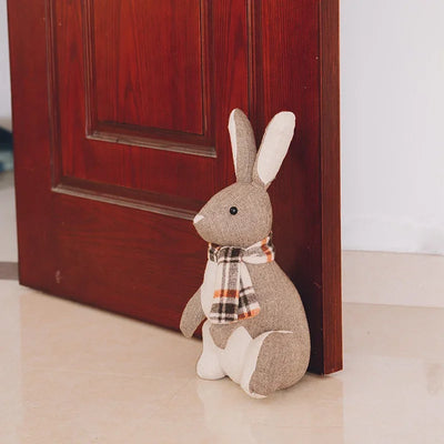 Cale-porte lapin en peluche gris clair sur sol carrelé