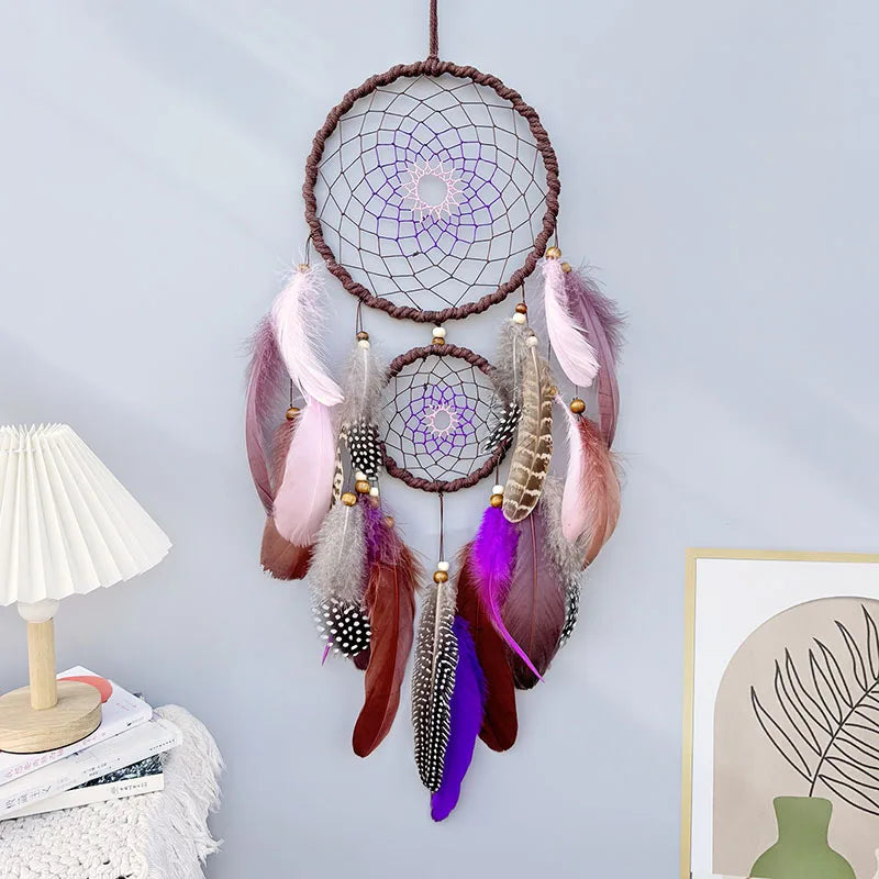 Un magnifique attrape-rêves violet et rose suspendu, orné de plumes colorées et de perles, créant une atmosphère apaisante et méditative dans la pièce.