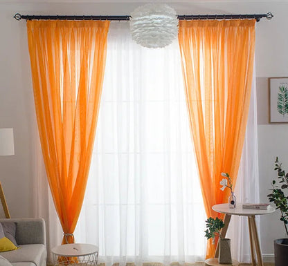 Voilage orange lumineux installé dans un salon moderne, encadrant une baie vitrée avec des murs blancs et une décoration naturelle.