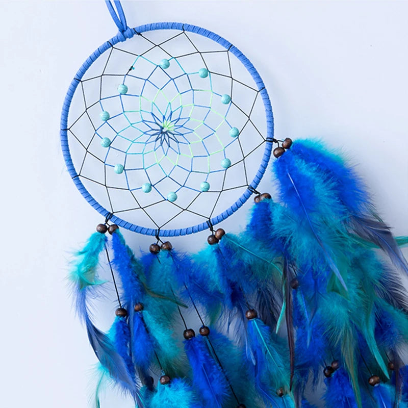 Un capteur de rêves bleu avec un motif en forme d'étoile et des plumes bleues et vertes, suspendu sur un fond blanc.