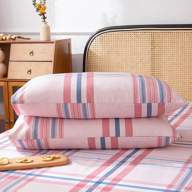 Des oreillers aux motifs colorés et rayés, avec une table de chevet en bois et un joli vase fleuri dans un décor cocooning et chaleureux.