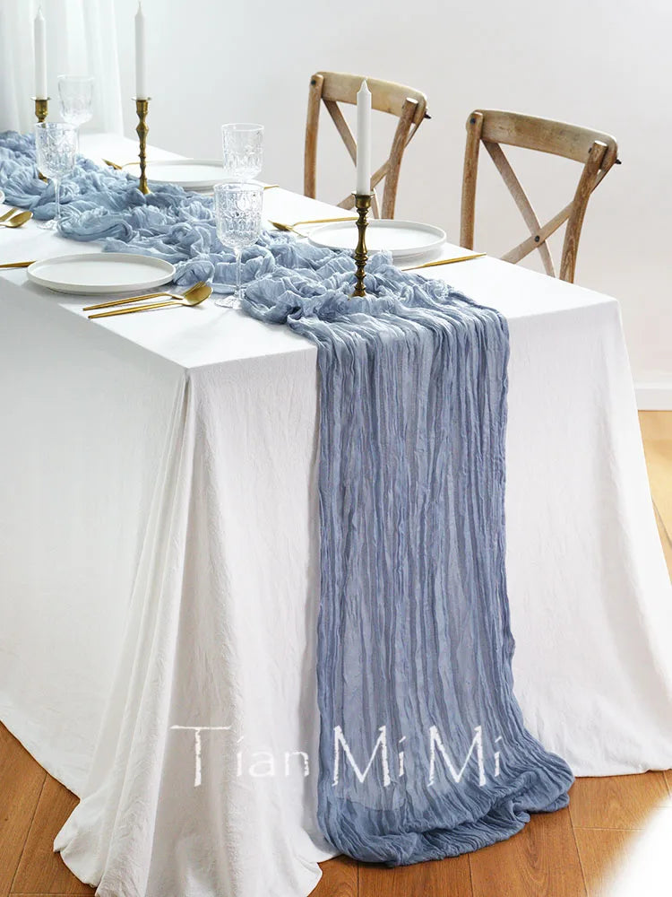 Magnifique table dressée pour un repas avec une nappe blanche, une chemin de table et des décorations en bleu et doré, créant une ambiance élégante et raffinée.