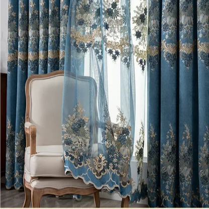 Rideau tulle bleu pétrole brodé avec détails dorés, flottant devant un fauteuil vintage en bois sculpté et tissu beige, dans un salon raffiné.