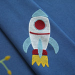 Broderie de fusée colorée sur fond bleu, parfait pour personnalisations créatives et décoration textile originale. Idéal pour ajout de motifs ludiques sur vêtements enfants. Design attrayant et dynamique pour stimuler l'imagination.