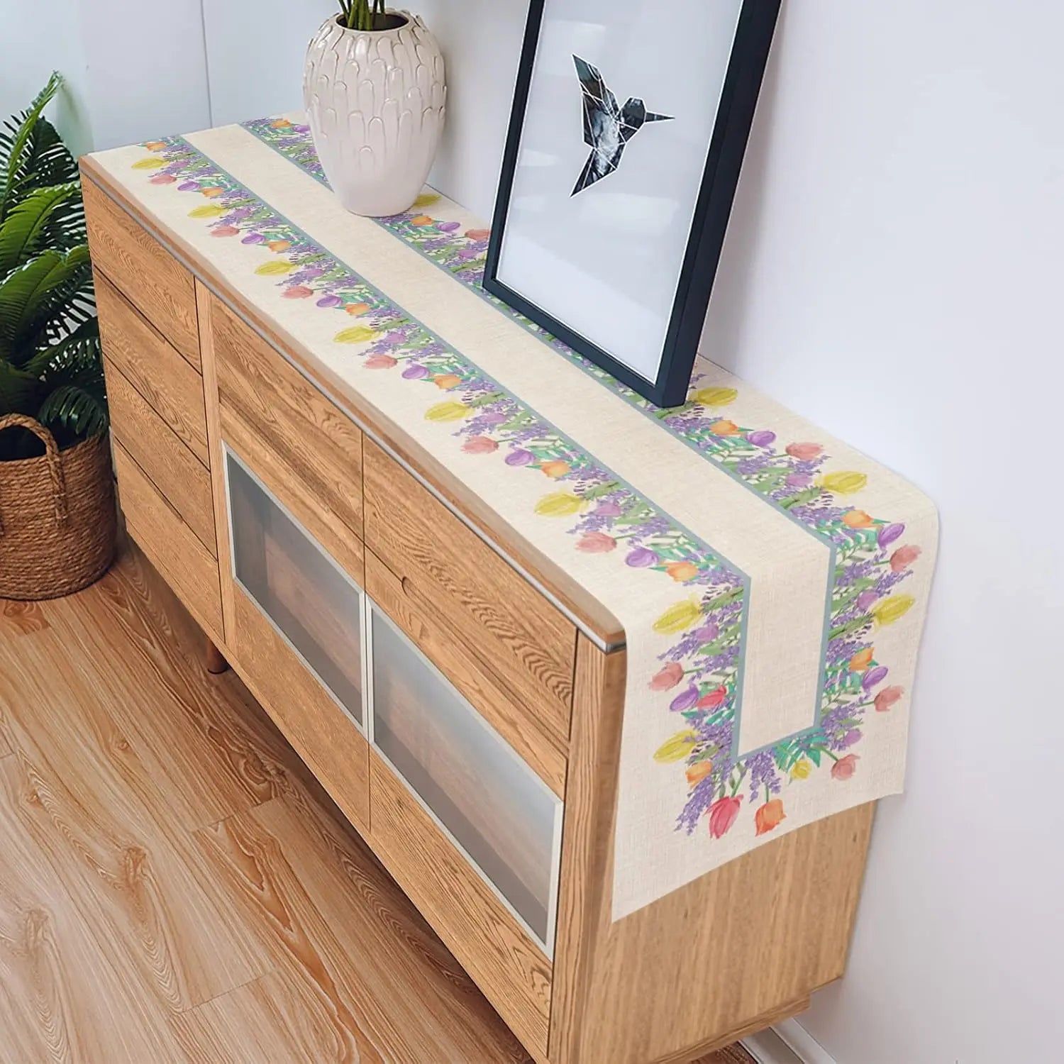 Sur le meuble en bois, un chemin de table coloré et floral ajoute une touche de design et de fraîcheur à l'espace.