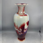 Vase élégant à motifs abstraits rouges et bleus, avec un fini brillant et une forme élancée.
