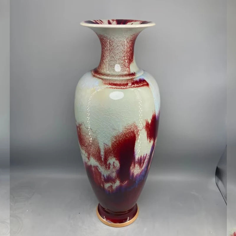 Vase élégant à motifs abstraits rouges et bleus, avec un fini brillant et une forme élancée.