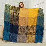 Une couverture décorative en patchwork jaune et bleue aux motifs floraux élégants.